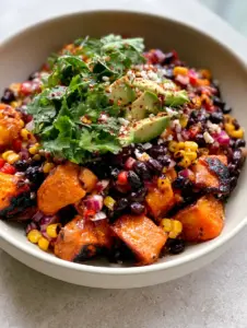 A large matte white bowl filled with glossy black beans and chunky roasted sweet potato cubes with blistered edges. (black bean salad with sweet potato)