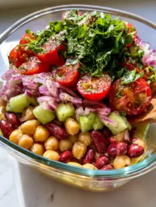 High-angle shot of a Mediterranean Bean and Chickpea Salad showing glossy beans and fresh parsley topping. (Bean and Chickpea Salad)