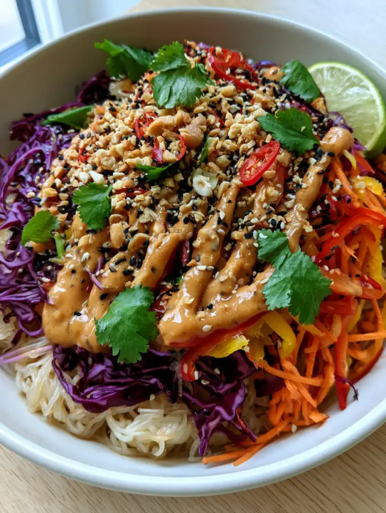 Vegetable Rice Noodle Salad with Creamy Peanut Dressing 2 Smartphone photo of a vegetable rice noodle salad with glistening noodles and bright orange carrots in a matte white bowl.