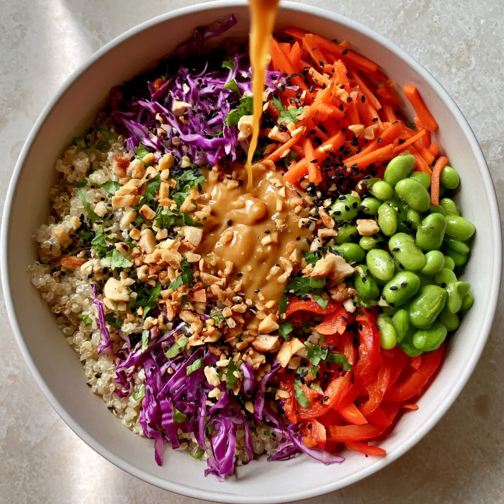 Thai-Inspired Quinoa Salad with Creamy Peanut Dressing 2 Top-down view of Thai-Inspired Quinoa Salad with sections of red pepper, edamame, and shredded cabbage topped with peanuts.