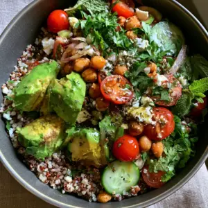 Overhead high-angle photo of a vibrant Mediterranean quinoa avocado salad in a charcoal ceramic bowl. (quinoa avocado salad)