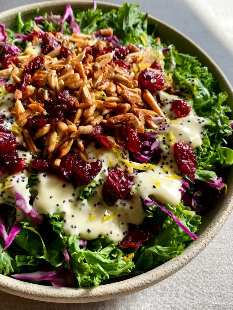 Overhead view of a sunflower crunch salad artistically drizzled with glossy ivory poppyseed dressing on a grey linen surface.