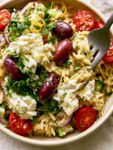 Close-up of Greek Orzo Pasta Salad showing individual glistening orzo grains and quartered cherry tomatoes.
