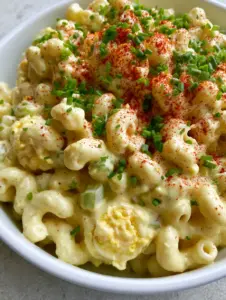 Macro eye-level shot of stuffed egg pasta salad showing glossy dressing and jammy egg yolks.