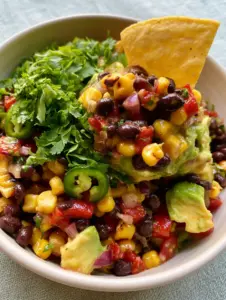 Close-up of plump black beans and golden charred corn kernels mixed with ruby red peppers in a black bean corn salad.